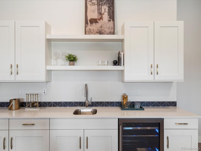 kitchen featuring white cabinets, sink, and beverage cooler