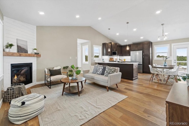 11840 Elkhorn Dr, Franktown, CO 80116 - living area with vaulted ceiling, light wood-type flooring, a fireplace, recessed lighting, and a chandelier