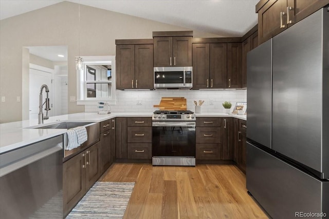 11840 Elkhorn Dr, Franktown, CO 80116 - kitchen with stainless steel appliances, vaulted ceiling, dark brown cabinets, light wood finished floors, and light countertops