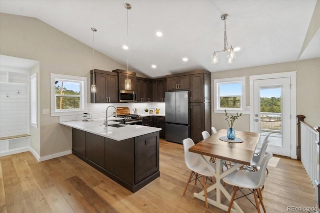 11840 Elkhorn Dr, Franktown, CO 80116 - kitchen featuring stainless steel appliances, vaulted ceiling, a sink, dark brown cabinets, and a peninsula
