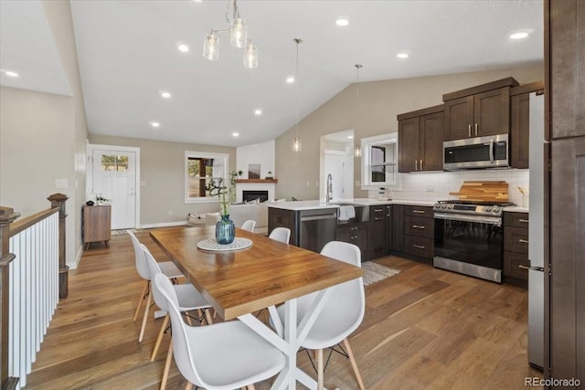 11840 Elkhorn Dr, Franktown, CO 80116 - dining space featuring vaulted ceiling, wood finished floors, a fireplace, and recessed lighting