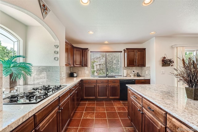 kitchen featuring stainless steel gas cooktop, dark tile patterned flooring, dishwasher, sink, and decorative backsplash