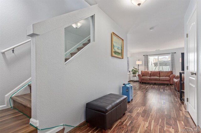 hall featuring a textured wall, wood finished floors, and stairway