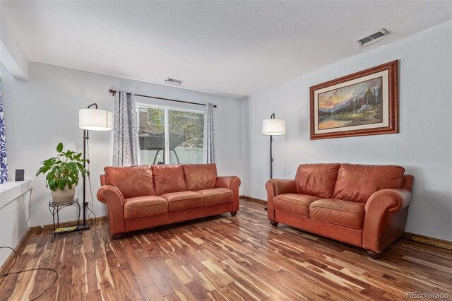 living area with visible vents, baseboards, and wood finished floors
