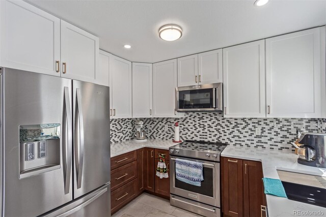kitchen with dark brown cabinets, appliances with stainless steel finishes, light countertops, white cabinetry, and tasteful backsplash