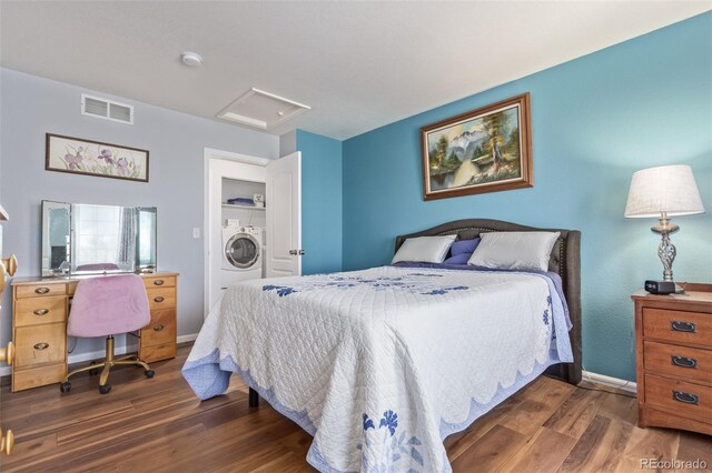 bedroom with visible vents, washer / dryer, wood finished floors, baseboards, and attic access