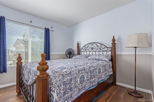 bedroom with baseboards, wood finished floors, and multiple windows