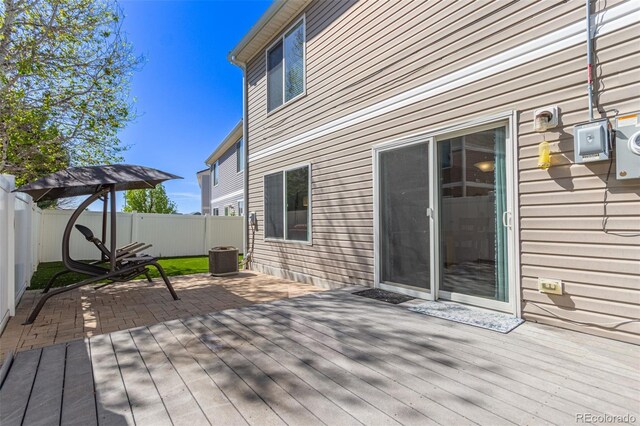 wooden terrace with a fenced backyard, central AC unit, and a patio area