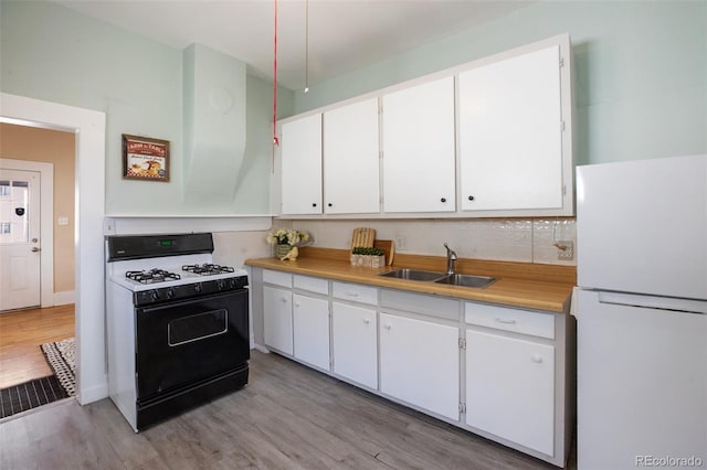 112 S Limit St, Colorado Springs, CO 80905 - kitchen with white cabinetry, a sink, freestanding refrigerator, and gas stove