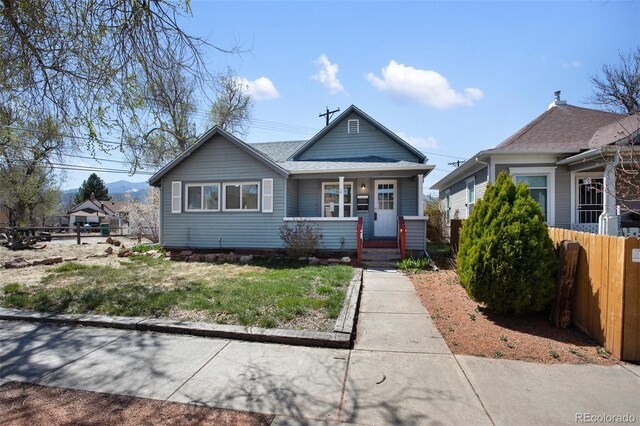 112 S Limit St, Colorado Springs, CO 80905 - bungalow-style home featuring a porch, fence, and a front lawn