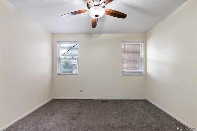 empty room featuring dark carpet, ceiling fan, and plenty of natural light