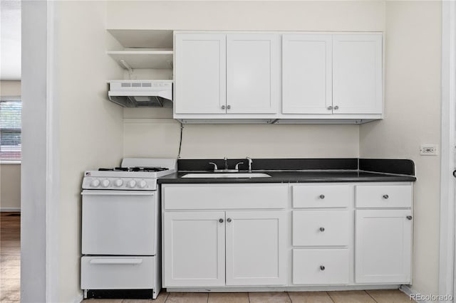 kitchen featuring white range, white cabinetry, light tile patterned floors, and sink