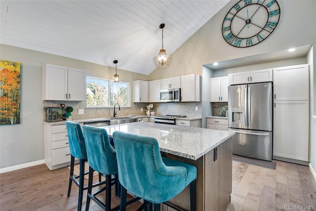 kitchen with a center island, white cabinetry, stainless steel appliances, and light hardwood / wood-style flooring