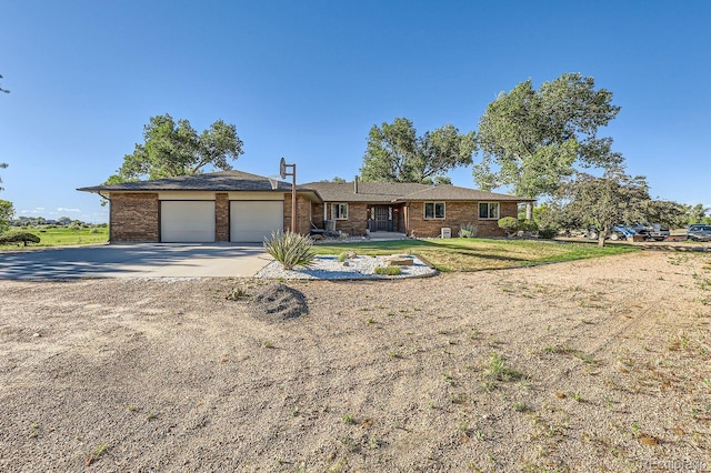 ranch-style house featuring a garage, brick siding, concrete driveway, and a front yard