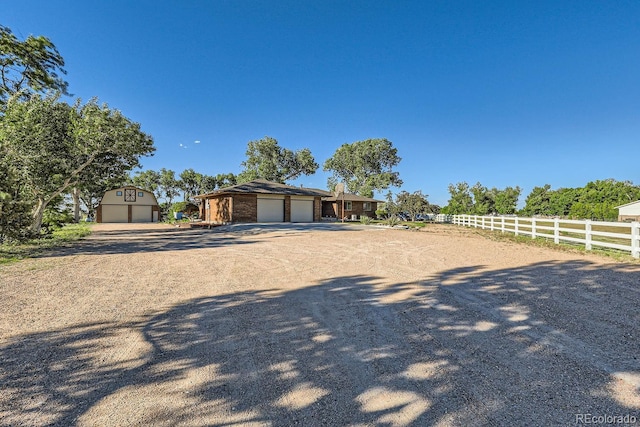 view of front of property featuring an outbuilding, a garage, fence, driveway, and a storage unit