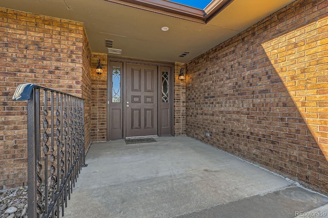 property entrance featuring visible vents and brick siding