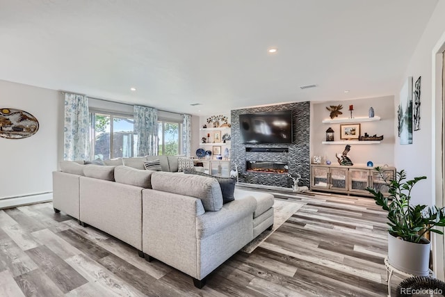 living area with a fireplace, recessed lighting, visible vents, a baseboard heating unit, and wood finished floors