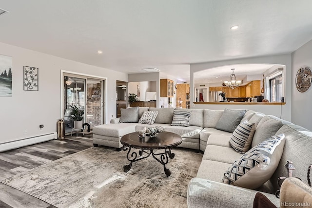 living area with arched walkways, recessed lighting, a baseboard heating unit, wood finished floors, and an inviting chandelier