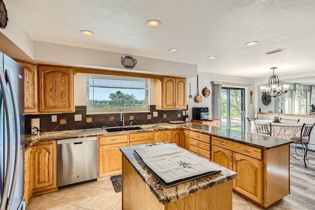 kitchen featuring stainless steel appliances, tasteful backsplash, visible vents, a sink, and a peninsula