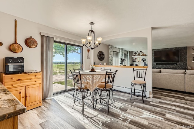 dining area featuring light wood-style floors, a baseboard radiator, and a notable chandelier