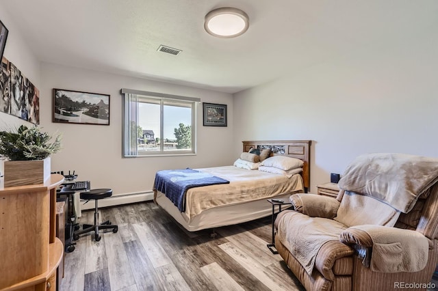 bedroom featuring baseboard heating, wood finished floors, and visible vents