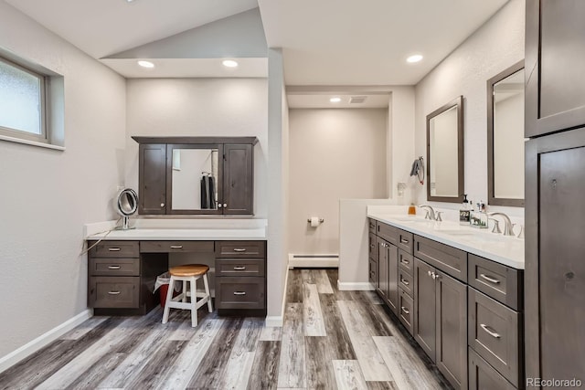 bathroom featuring a baseboard heating unit, wood finished floors, a sink, and double vanity