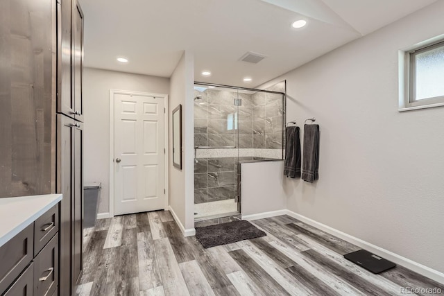 full bathroom featuring a stall shower, wood finished floors, visible vents, and baseboards