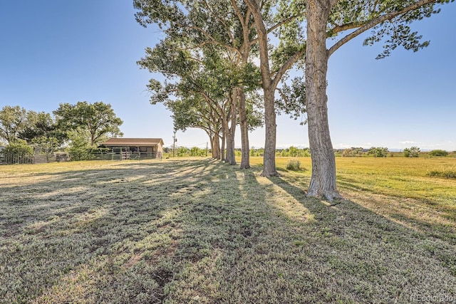 view of yard with an outbuilding, a rural view, an outdoor structure, and fence