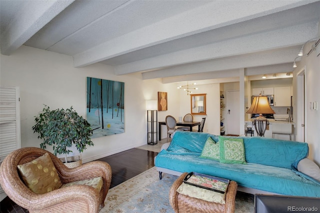 living area featuring baseboards, beam ceiling, an inviting chandelier, and wood finished floors