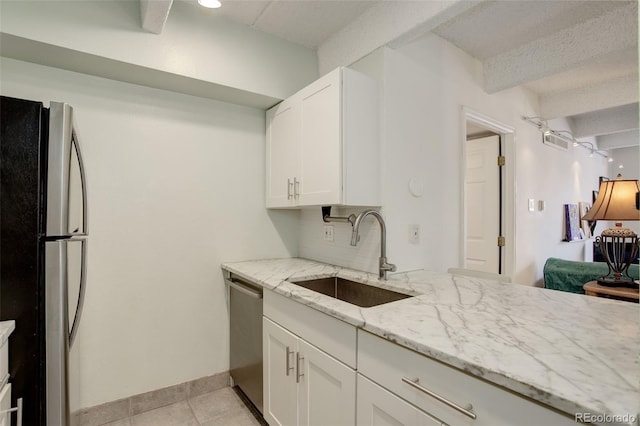 kitchen with a sink, light stone counters, white cabinetry, stainless steel appliances, and light tile patterned flooring