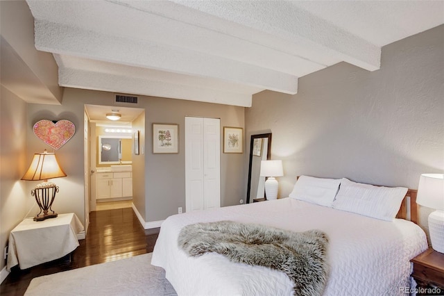 bedroom featuring visible vents, baseboards, beamed ceiling, wood finished floors, and a closet