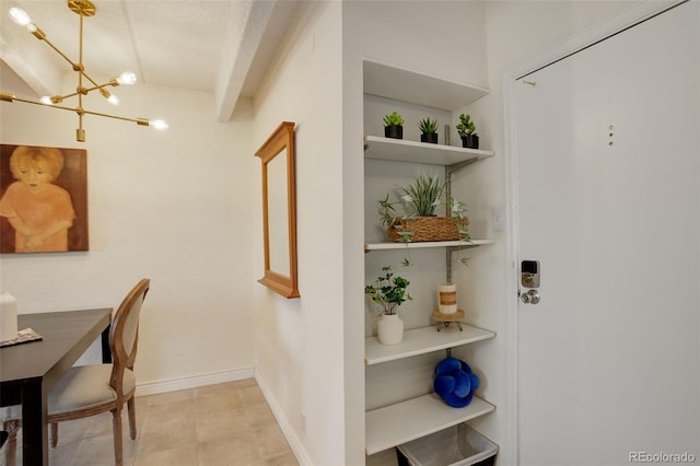 interior space with an inviting chandelier, light tile patterned floors, and baseboards