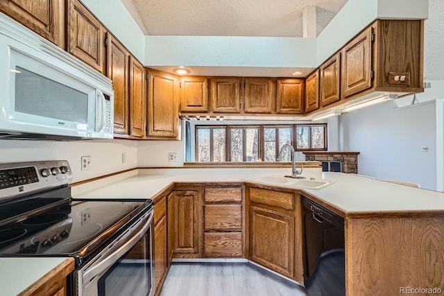 kitchen with electric range, a sink, black dishwasher, brown cabinetry, and white microwave