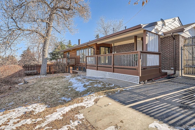 view of home's exterior featuring brick siding, a porch, and fence