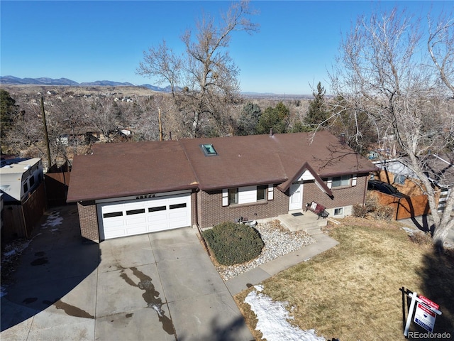 view of front of home with a garage, a mountain view, brick siding, and driveway