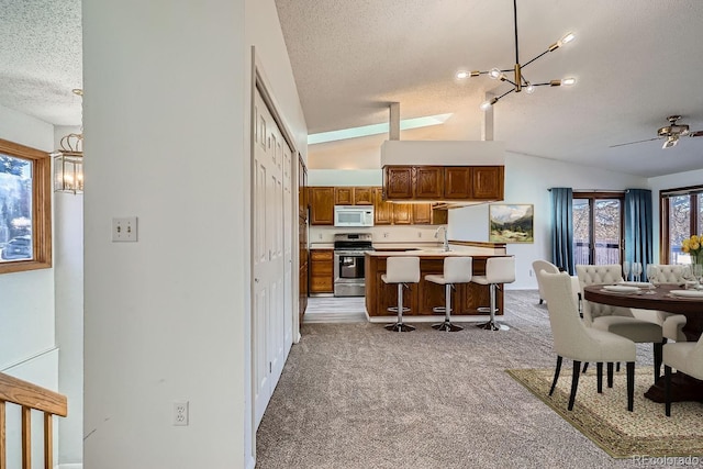 kitchen with white microwave, stainless steel electric stove, open floor plan, light carpet, and a textured ceiling