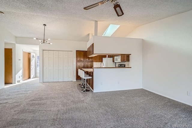 unfurnished living room featuring carpet flooring, ceiling fan with notable chandelier, a textured ceiling, and lofted ceiling