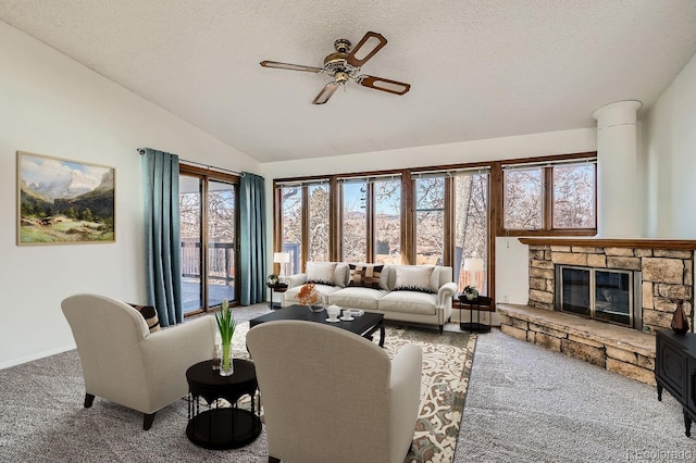 living area featuring carpet, vaulted ceiling, a stone fireplace, a textured ceiling, and a ceiling fan