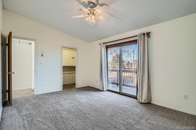 unfurnished bedroom with access to exterior, a spacious closet, lofted ceiling, and carpet floors