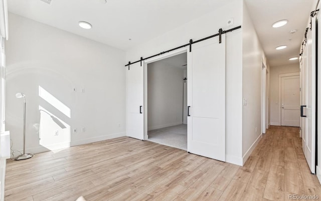 interior space with light wood-type flooring and a barn door