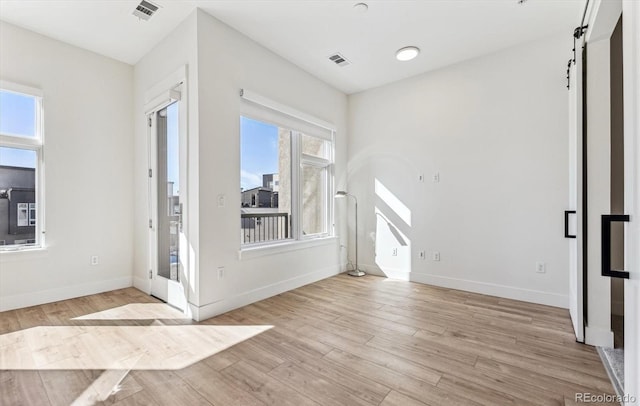 interior space featuring light wood-type flooring, a barn door, and a wealth of natural light