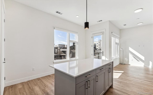 kitchen with pendant lighting, light hardwood / wood-style floors, gray cabinets, and a kitchen island