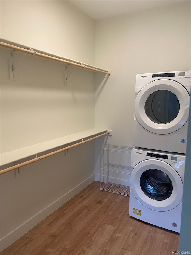 laundry area with stacked washer and clothes dryer and hardwood / wood-style flooring