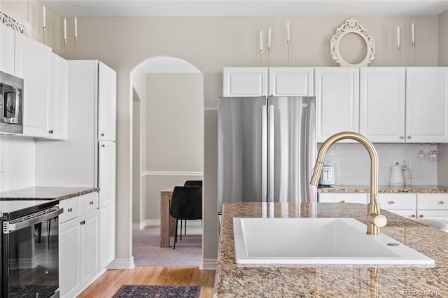 20740 Parker Vista Rd, Parker, CO 80138 - kitchen with appliances with stainless steel finishes, light stone counters, white cabinetry, and light wood finished floors