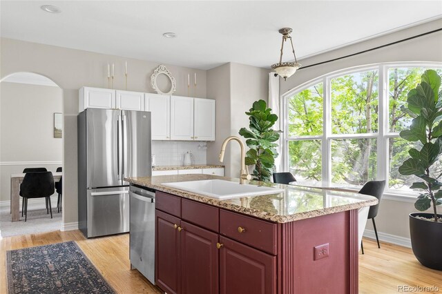20740 Parker Vista Rd, Parker, CO 80138 - kitchen featuring appliances with stainless steel finishes, dark brown cabinets, light wood-type flooring, backsplash, and arched walkways