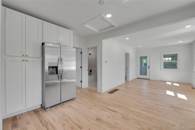 kitchen featuring stainless steel fridge, white cabinetry, and light hardwood / wood-style floors