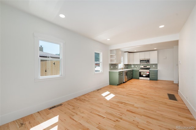 interior space with green cabinets, stainless steel appliances, light wood-type flooring, and white cabinetry