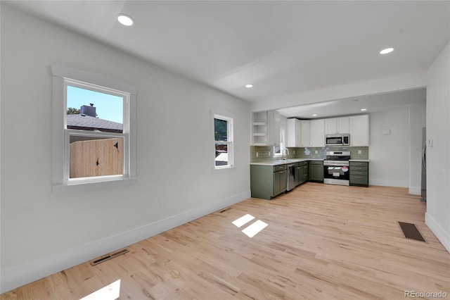 kitchen with light wood-type flooring, white cabinets, stainless steel appliances, and a healthy amount of sunlight