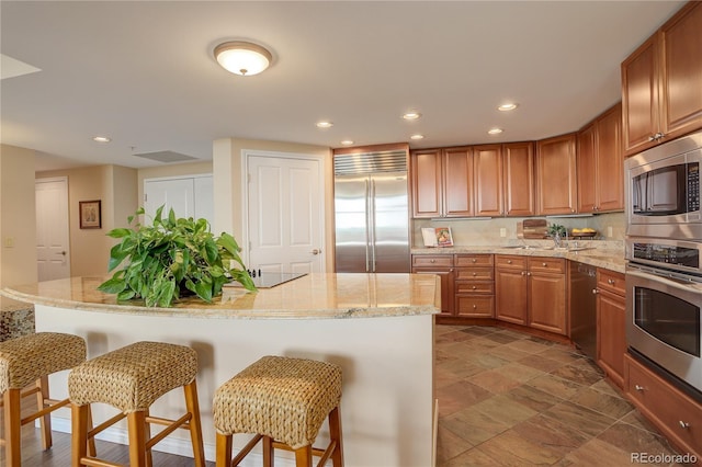 8100 E Union Ave Unit 1502, Denver, CO 80237 - kitchen with built in appliances, a kitchen bar, recessed lighting, a kitchen island, and brown cabinets