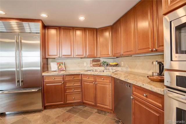 8100 E Union Ave Unit 1502, Denver, CO 80237 - kitchen featuring appliances with stainless steel finishes, a sink, brown cabinetry, recessed lighting, and light stone finish flooring